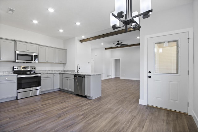 kitchen featuring dark wood-style floors, stainless steel appliances, gray cabinets, a sink, and a peninsula