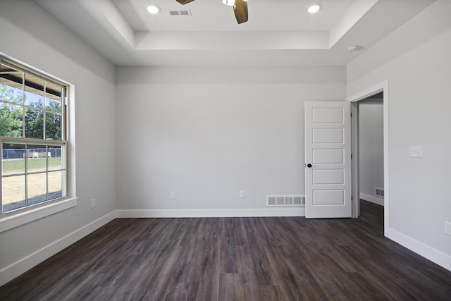 unfurnished room with dark wood finished floors, visible vents, and baseboards