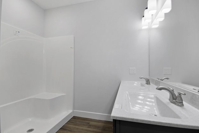 full bathroom with double vanity, baseboards, a sink, and wood finished floors