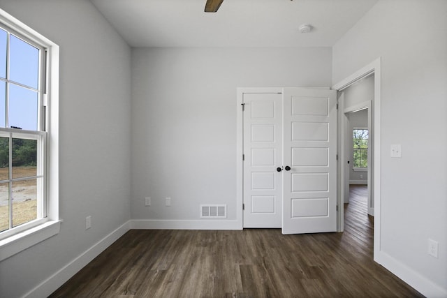 unfurnished bedroom featuring baseboards, visible vents, dark wood-style floors, ceiling fan, and a closet