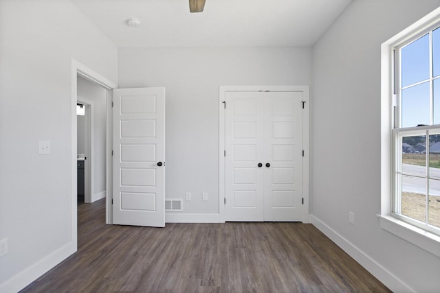 unfurnished bedroom with dark wood-style floors, a closet, visible vents, and baseboards