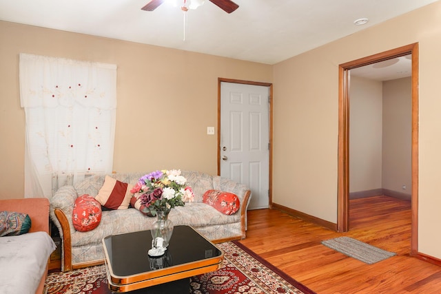 living room with light wood finished floors, baseboards, and a ceiling fan