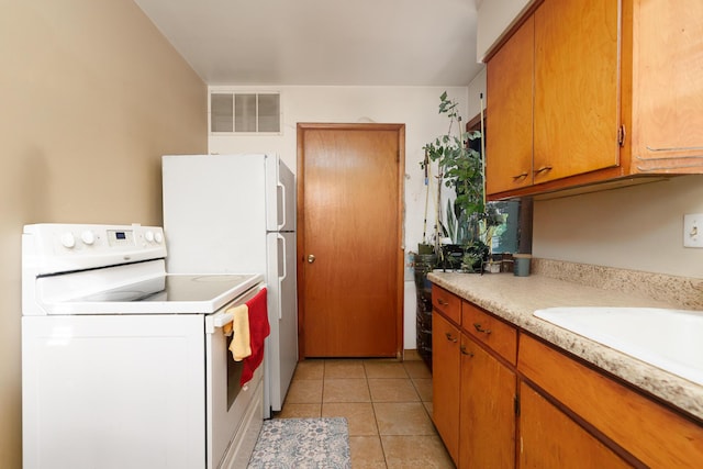 kitchen with light tile patterned floors, white appliances, visible vents, light countertops, and brown cabinets