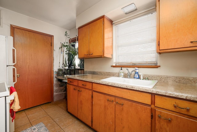 kitchen with brown cabinets, light countertops, light tile patterned flooring, a sink, and range