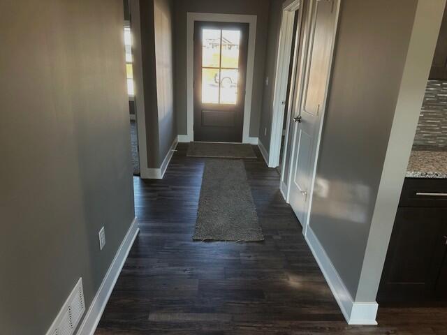 doorway with dark wood-style floors and baseboards