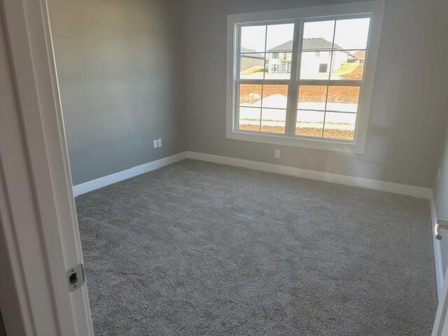 spare room featuring carpet floors and baseboards