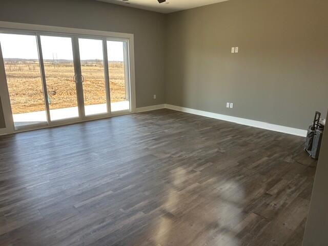 unfurnished room featuring dark wood-style flooring and baseboards