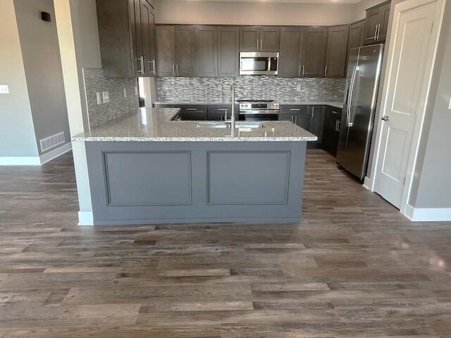 kitchen featuring dark wood-style floors, visible vents, backsplash, appliances with stainless steel finishes, and a peninsula