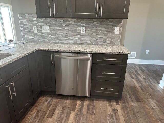 kitchen featuring dark wood-style floors, visible vents, stainless steel dishwasher, and light stone countertops