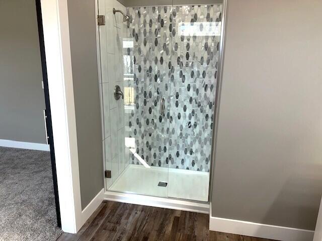 bathroom with a stall shower, wood finished floors, and baseboards