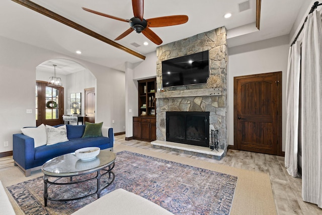 living area featuring visible vents, wood finished floors, arched walkways, a fireplace, and baseboards