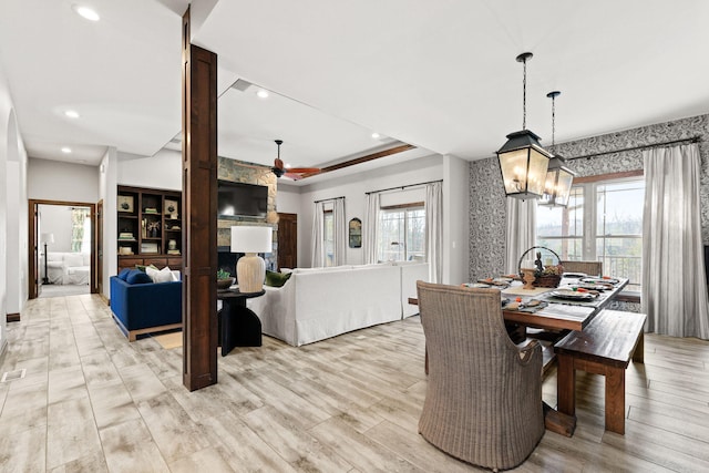 dining room featuring recessed lighting, a tray ceiling, ceiling fan with notable chandelier, and light wood finished floors