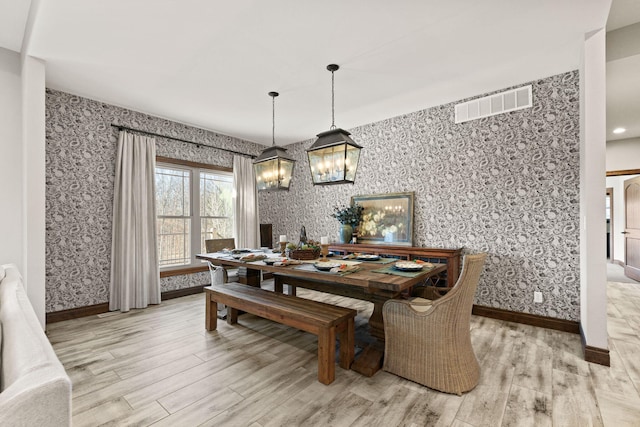 dining space with visible vents, wallpapered walls, light wood-type flooring, and baseboards