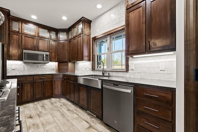 kitchen with decorative backsplash, dark brown cabinets, appliances with stainless steel finishes, and a sink