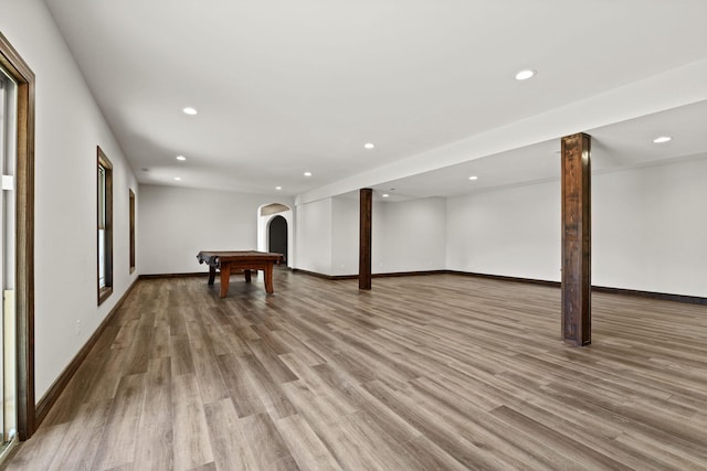 below grade area featuring recessed lighting, baseboards, arched walkways, and wood finished floors