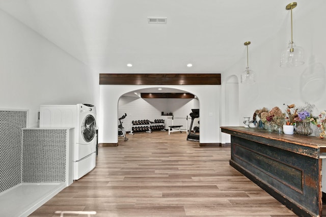 interior space featuring visible vents, baseboards, laundry area, wood finished floors, and arched walkways