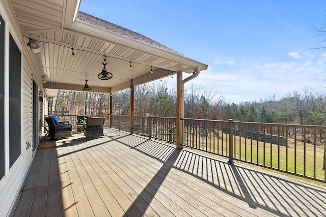 wooden terrace featuring a forest view, covered porch, and ceiling fan