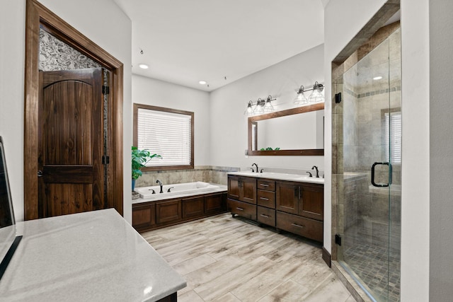 full bath featuring a stall shower, a sink, wood finished floors, double vanity, and a bath