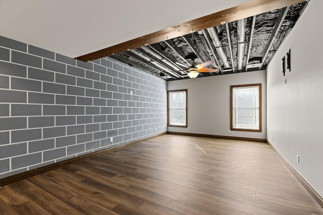 spare room featuring beam ceiling, wood finished floors, baseboards, and ceiling fan