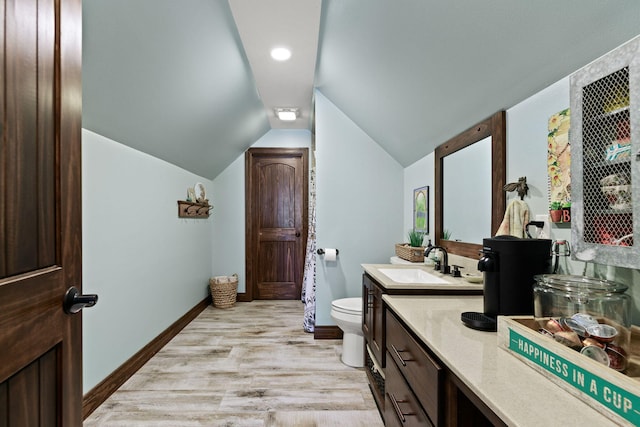 bathroom with vanity, wood finished floors, baseboards, lofted ceiling, and toilet