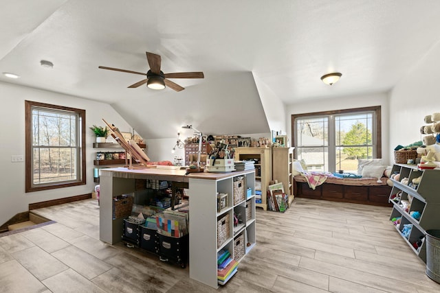 interior space featuring a ceiling fan, vaulted ceiling, light wood-style floors, and a wealth of natural light