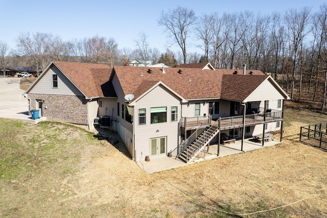 rear view of property with stairway, roof with shingles, french doors, a deck, and a patio