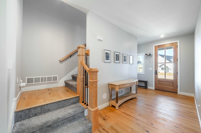 foyer entrance with stairs, baseboards, visible vents, and light wood-style floors