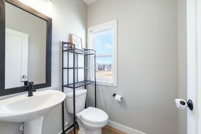 bathroom featuring baseboards, a sink, and toilet