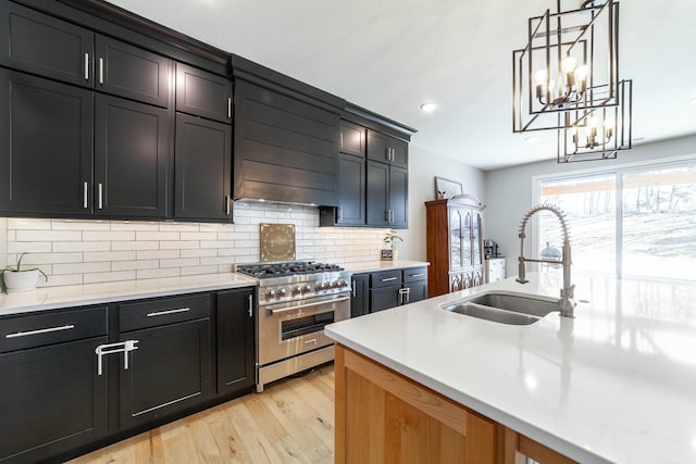 kitchen featuring exhaust hood, a sink, light countertops, light wood-type flooring, and stainless steel range