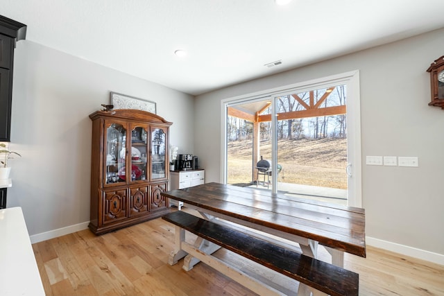 dining space with light wood-style flooring, visible vents, and baseboards