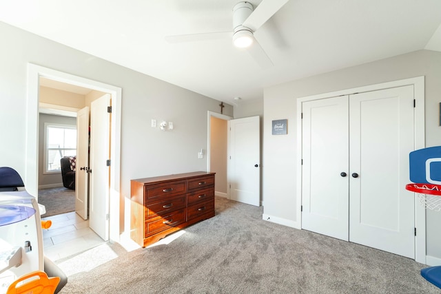 bedroom featuring baseboards, a ceiling fan, a closet, and light colored carpet