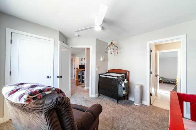 living area with a ceiling fan, light colored carpet, and baseboards