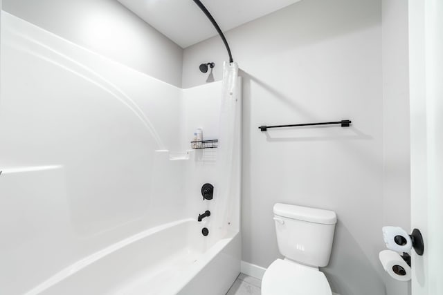 bathroom featuring toilet, washtub / shower combination, and baseboards