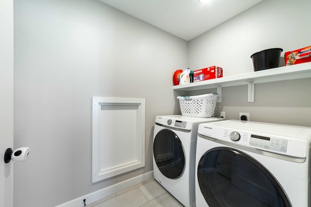 laundry room with light tile patterned floors, baseboards, and washer and clothes dryer