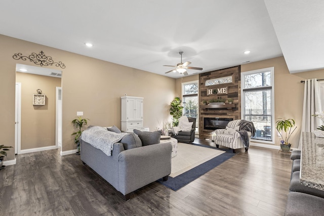 living area featuring recessed lighting, baseboards, a large fireplace, and dark wood-type flooring