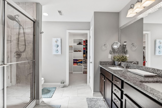 full bathroom featuring visible vents, double vanity, a sink, a shower stall, and a walk in closet