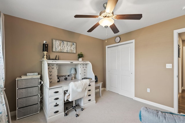 office area with ceiling fan, baseboards, and light carpet