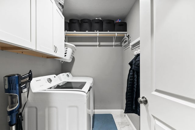 laundry area featuring baseboards, cabinet space, marble finish floor, and washer and clothes dryer