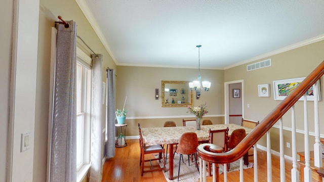 dining room with a notable chandelier, visible vents, baseboards, light wood finished floors, and crown molding