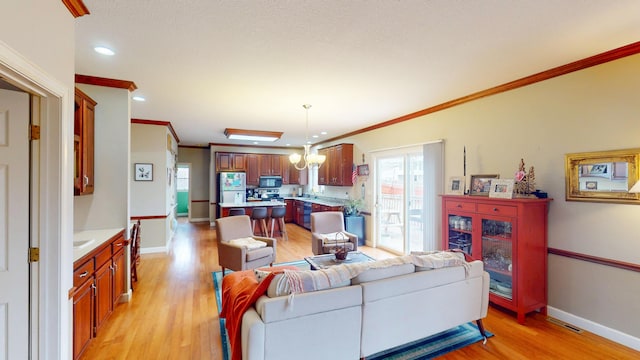 living area featuring a chandelier, light wood finished floors, ornamental molding, and baseboards