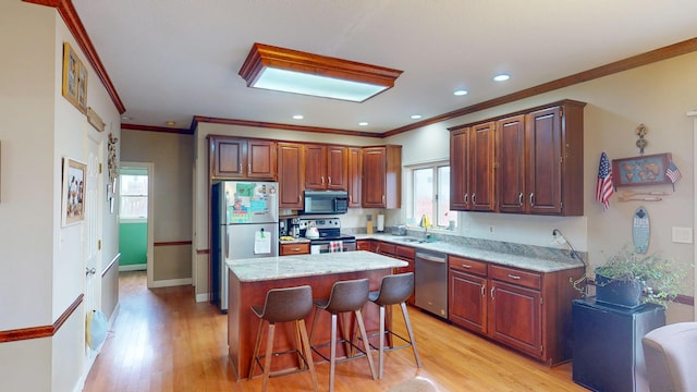 kitchen featuring appliances with stainless steel finishes, plenty of natural light, a sink, and light wood finished floors