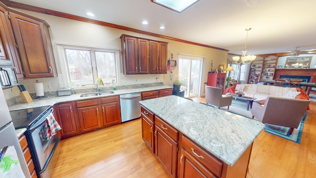 kitchen with a center island, crown molding, appliances with stainless steel finishes, a sink, and light wood-type flooring