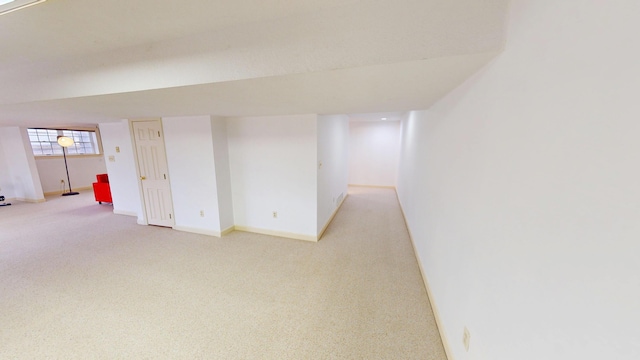 below grade area featuring baseboards and light colored carpet