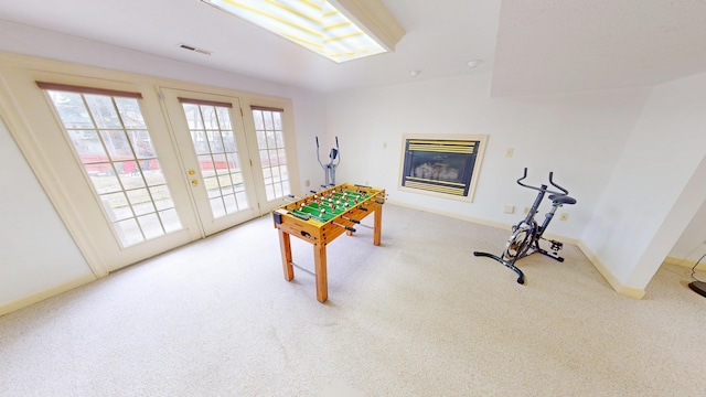 recreation room featuring carpet, visible vents, baseboards, and a glass covered fireplace