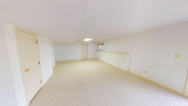 unfurnished room featuring light carpet and baseboards