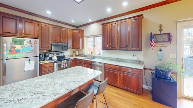 kitchen with stainless steel appliances, a sink, light wood-type flooring, light stone countertops, and a kitchen bar