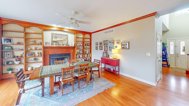 dining area with a fireplace, visible vents, light wood-style flooring, ornamental molding, and baseboards