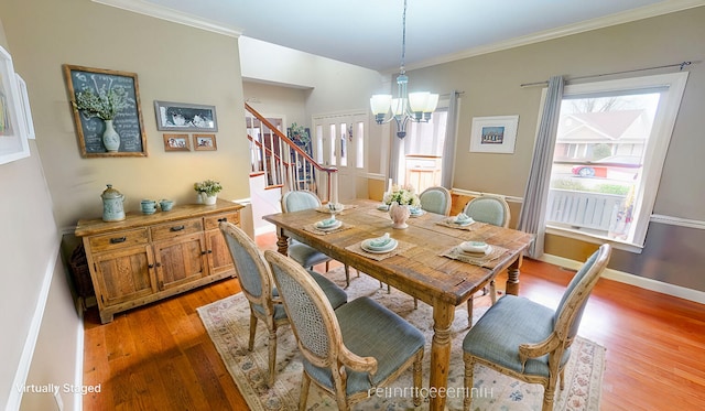 dining space with light wood-type flooring, baseboards, stairs, and ornamental molding