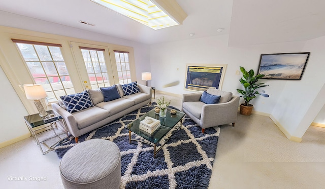 living room featuring a wealth of natural light, visible vents, a glass covered fireplace, and carpet