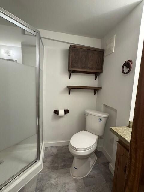 full bath featuring baseboards, toilet, a stall shower, and vanity